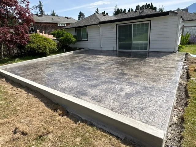 Large stamped concrete patio with slate pattern and concrete border in residential backyard