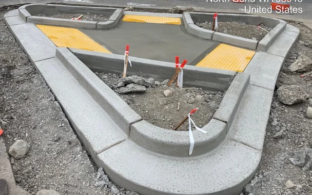 Newly poured concrete curb and gutter with yellow protective covers and red safety markers