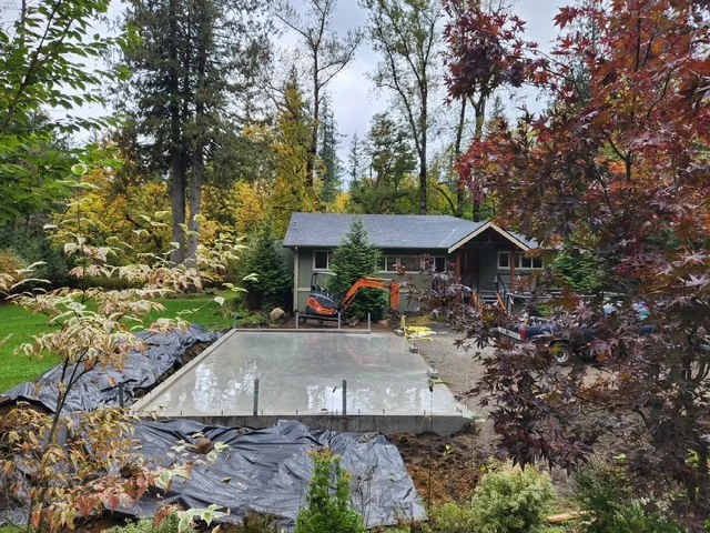 Finished concrete pad installation at residential home with autumn trees and landscaping