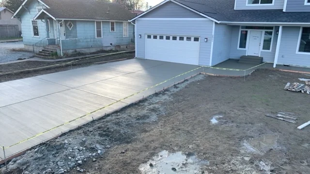 Newly poured concrete driveway with finished surface next to white garage
