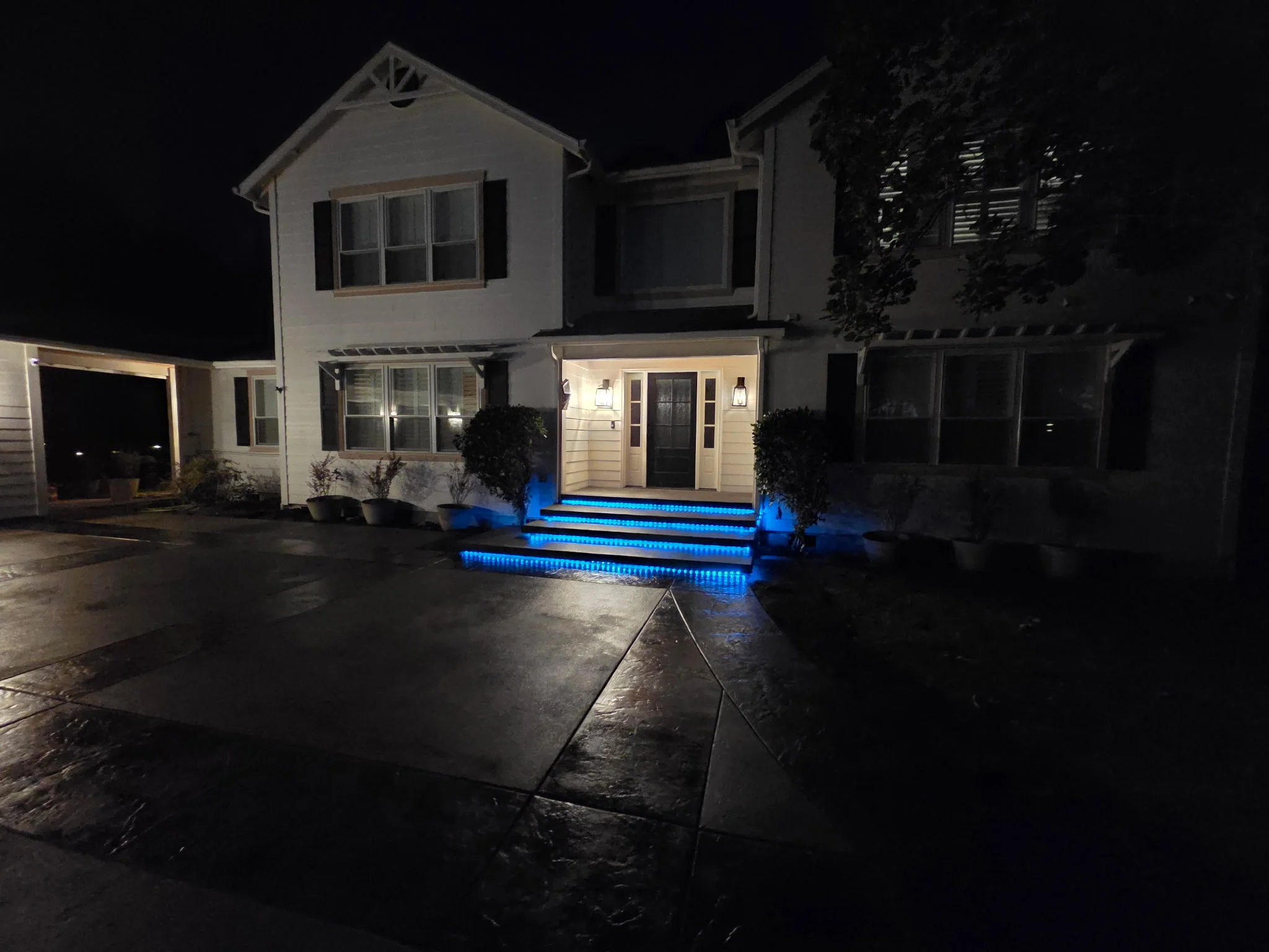 Concrete steps with blue LED lighting illuminating treads at residential home entrance