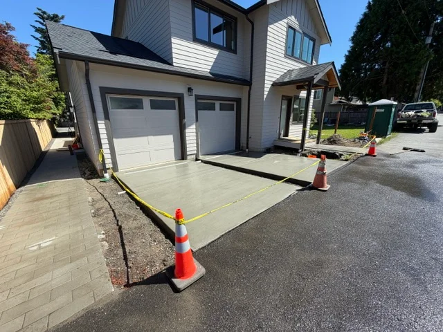 Fresh concrete driveway apron with control joints in front of residential garage